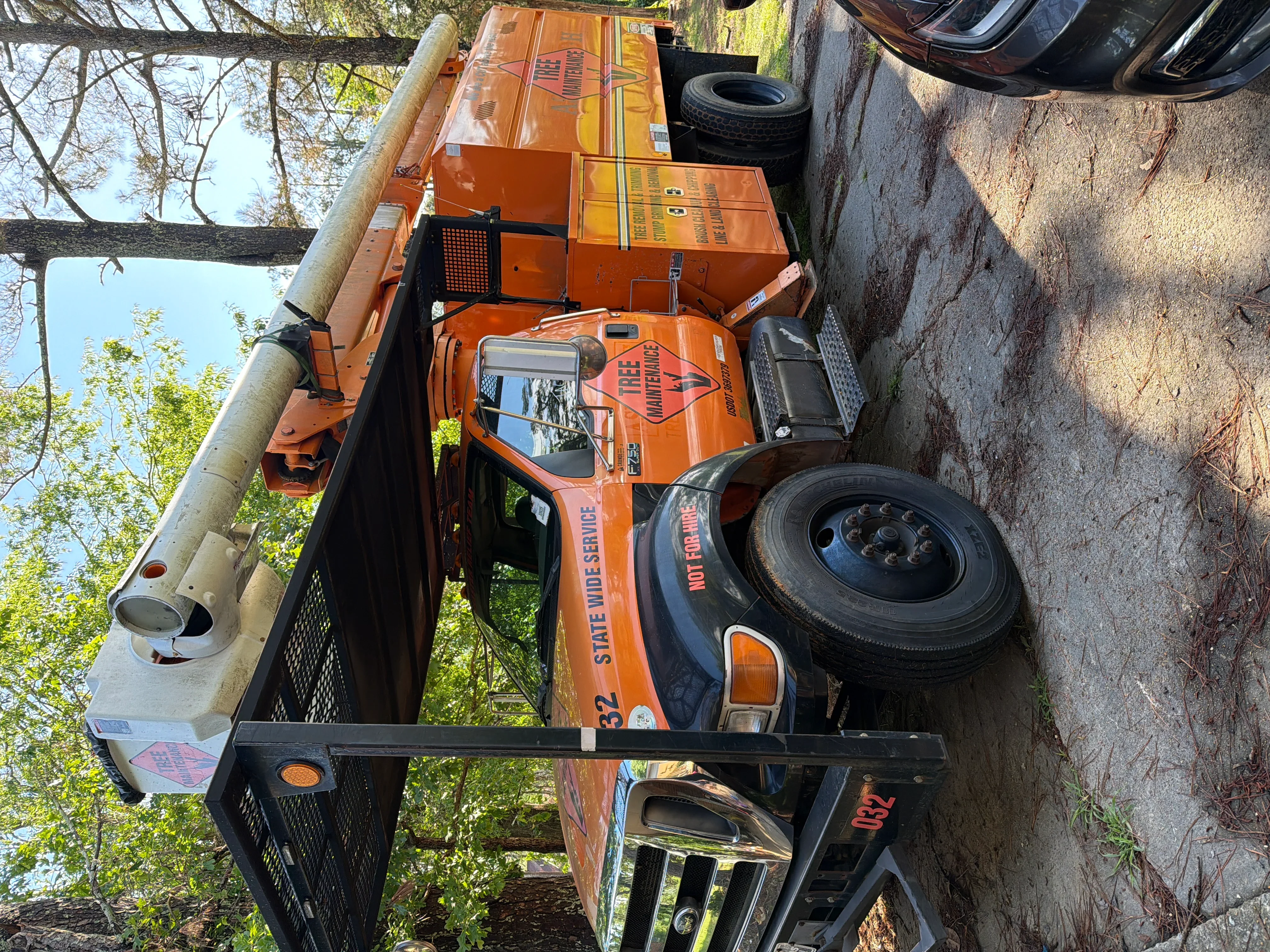 Orange tree service truck with debris removal equipment and metal cargo bed